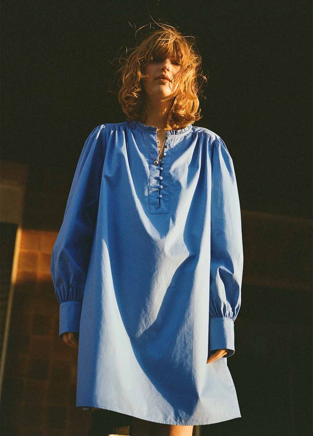 Жінка-модель на показі моди одягнена у блакитну кежуал сукню а-силует