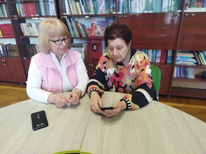 Бібліотекарка читальної зали Наталія Тимошенко допомагає освоїти смартфон Людмилі Біденко